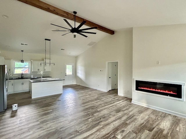 unfurnished living room featuring beamed ceiling, hardwood / wood-style floors, ceiling fan, and sink