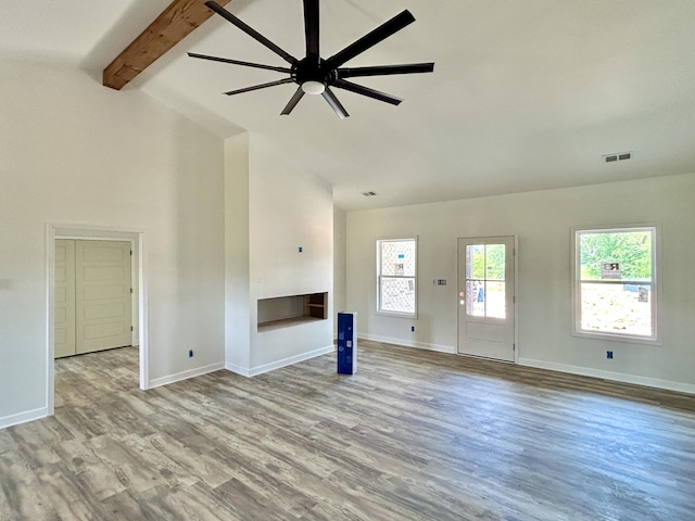 unfurnished living room with vaulted ceiling with beams, ceiling fan, a fireplace, and light hardwood / wood-style flooring