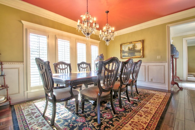 dining area with a wainscoted wall, ornamental molding, wood finished floors, a chandelier, and a decorative wall