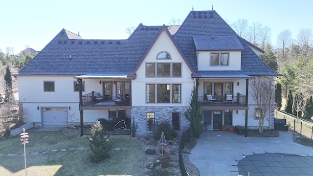 view of front of house featuring stone siding, driveway, a balcony, and stucco siding