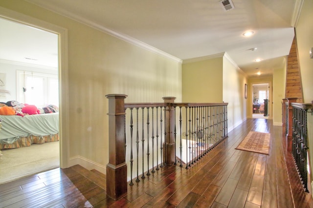 corridor with crown molding, visible vents, dark wood finished floors, and an upstairs landing