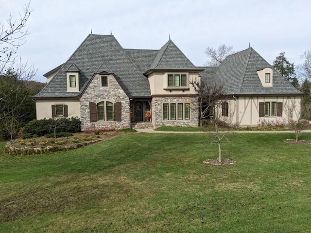 french provincial home with stone siding, a front lawn, and stucco siding