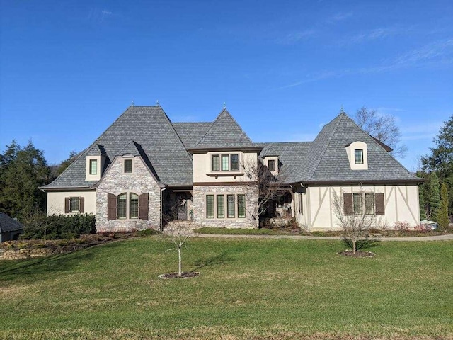 french country inspired facade with stone siding, stucco siding, and a front yard