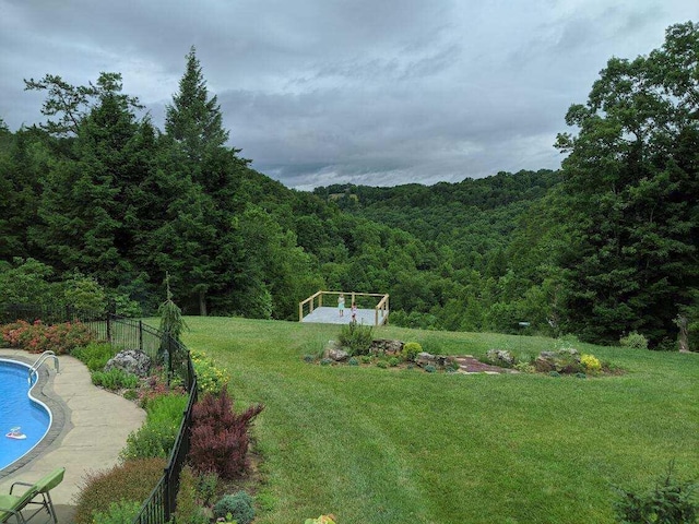 view of yard featuring a fenced in pool, fence, and a view of trees