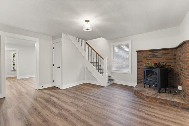 unfurnished living room with wood-type flooring, a textured ceiling, and a wood stove