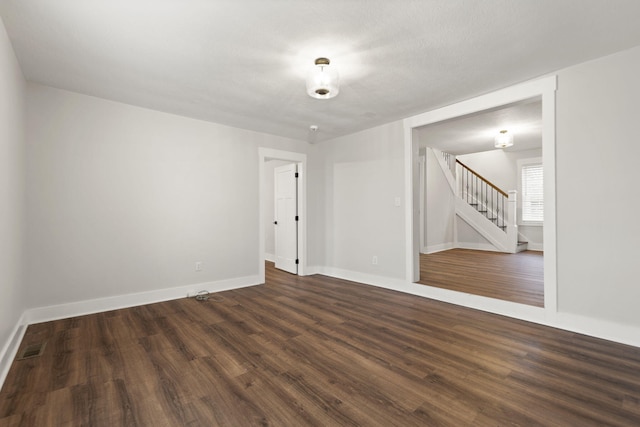 unfurnished room featuring dark wood-type flooring and a textured ceiling