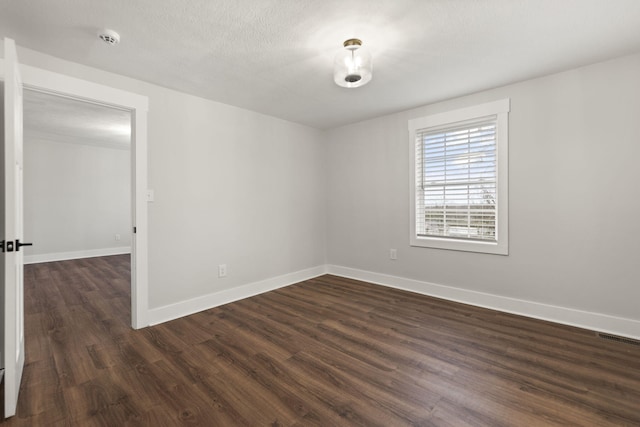 empty room featuring a textured ceiling and dark hardwood / wood-style flooring