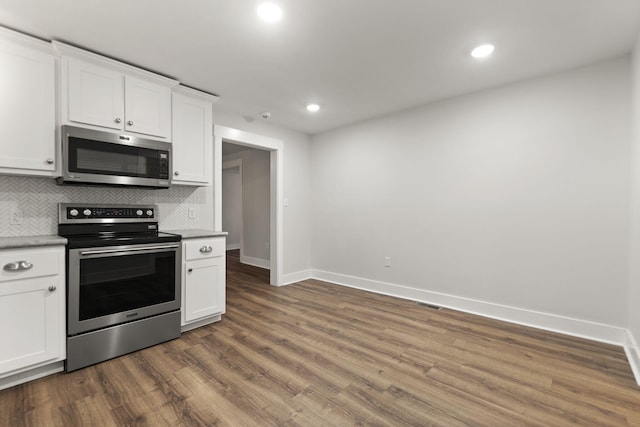 kitchen with decorative backsplash, white cabinets, stainless steel appliances, and dark hardwood / wood-style floors