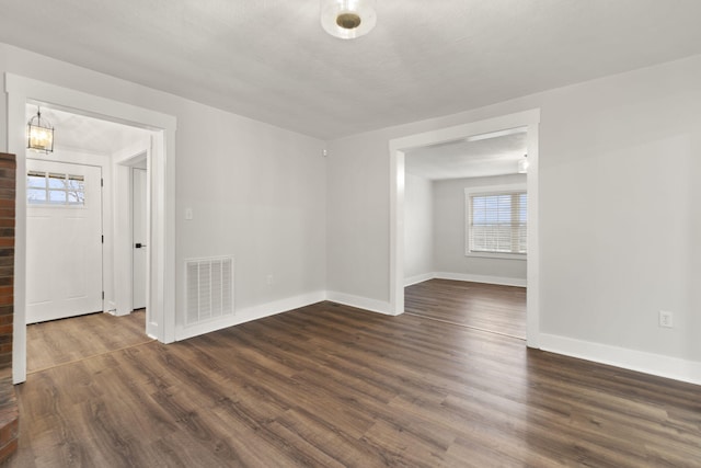 empty room featuring a textured ceiling and dark wood-type flooring