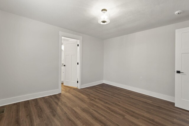 empty room with a textured ceiling and dark wood-type flooring