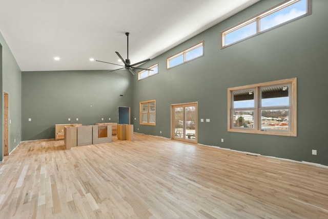 unfurnished living room with light hardwood / wood-style floors, a high ceiling, and ceiling fan