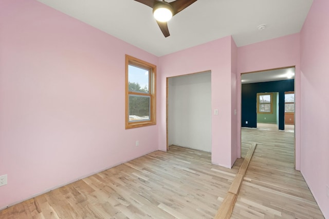 unfurnished bedroom featuring ceiling fan, a closet, multiple windows, and light hardwood / wood-style floors