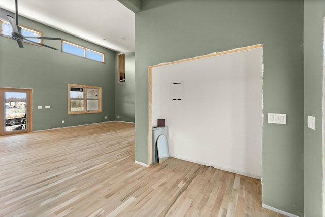 spare room with ceiling fan, a towering ceiling, and light hardwood / wood-style flooring