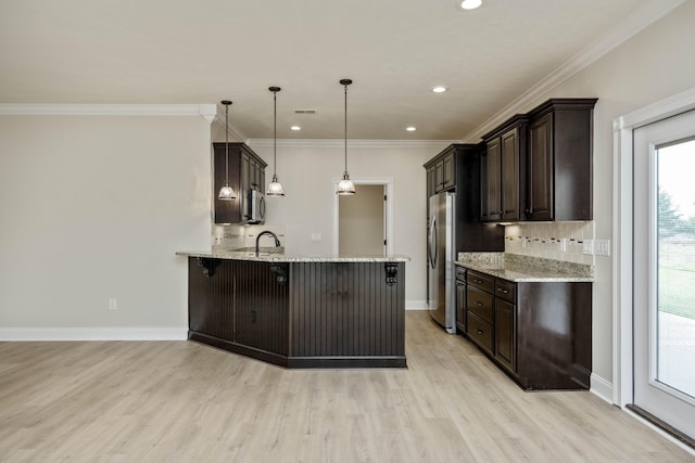 kitchen featuring a breakfast bar, hanging light fixtures, light stone countertops, light hardwood / wood-style floors, and kitchen peninsula