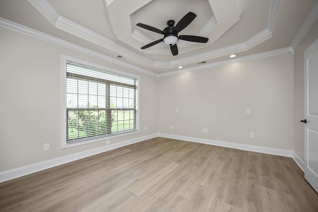 empty room featuring ceiling fan, a raised ceiling, light wood-type flooring, and crown molding