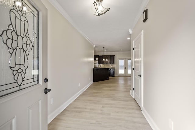 foyer entrance featuring light wood-type flooring, ornamental molding, and french doors