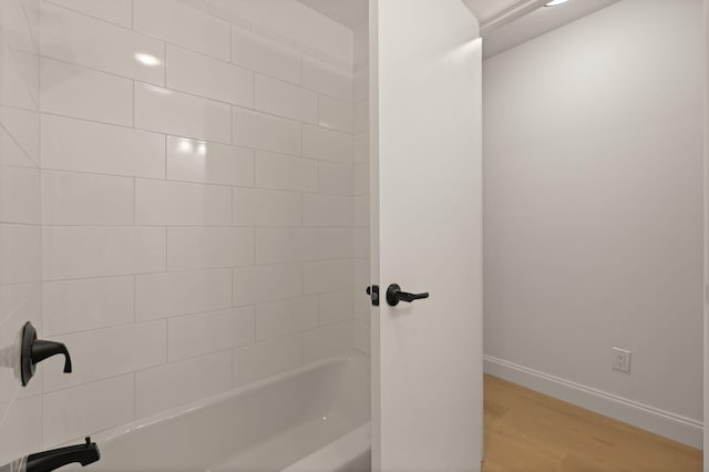 bathroom featuring wood-type flooring and tiled shower / bath