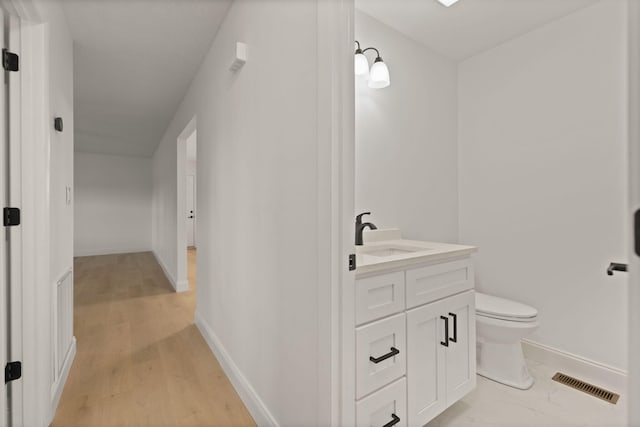 bathroom with toilet, vanity, and hardwood / wood-style flooring