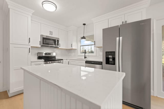 kitchen featuring pendant lighting, a center island, sink, appliances with stainless steel finishes, and white cabinetry