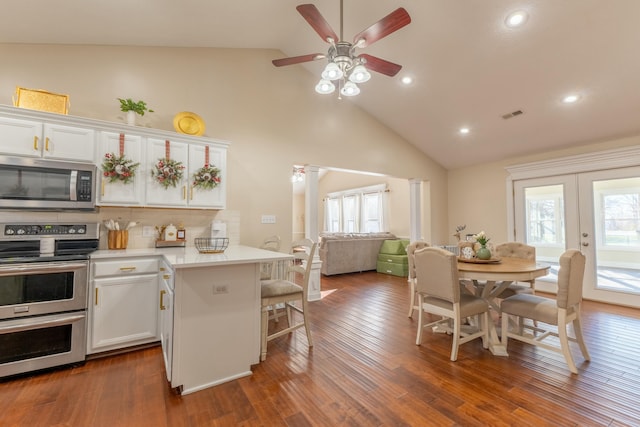 kitchen featuring decorative columns, stainless steel appliances, ceiling fan, white cabinets, and dark hardwood / wood-style floors