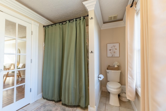 bathroom with toilet, a textured ceiling, tile patterned floors, and crown molding