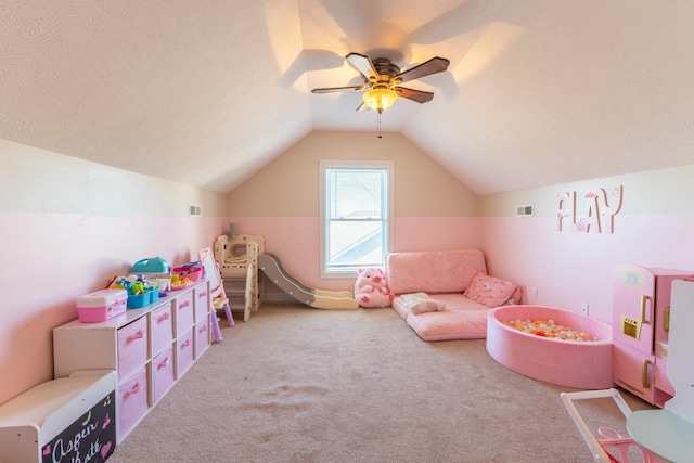 game room featuring a textured ceiling, carpet floors, vaulted ceiling, and ceiling fan