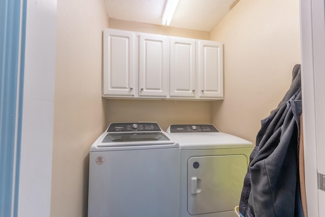 laundry area featuring washing machine and dryer, cabinets, and a textured ceiling