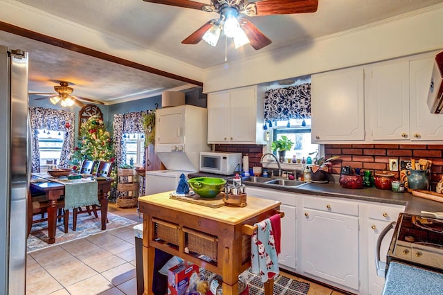 kitchen featuring sink, white cabinetry, crown molding, white appliances, and stacked washing maching and dryer