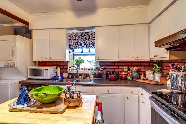 kitchen featuring stacked washer and dryer, extractor fan, sink, white cabinetry, and ornamental molding