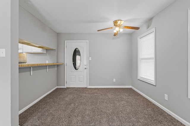 foyer entrance featuring ceiling fan and carpet