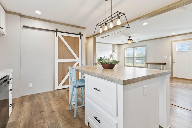 kitchen featuring pendant lighting, white cabinets, a center island, ceiling fan, and a barn door