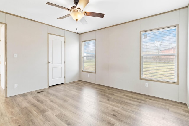 empty room with ceiling fan, ornamental molding, and light hardwood / wood-style flooring