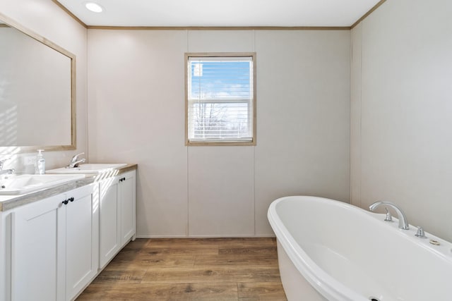 bathroom with hardwood / wood-style flooring, vanity, ornamental molding, and a bathtub