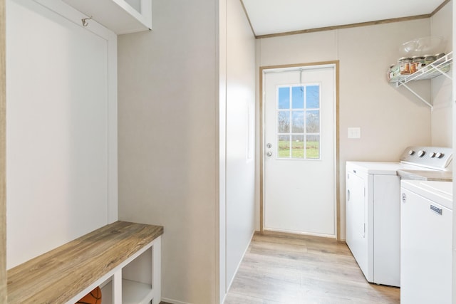 washroom featuring crown molding, washing machine and clothes dryer, and light hardwood / wood-style floors