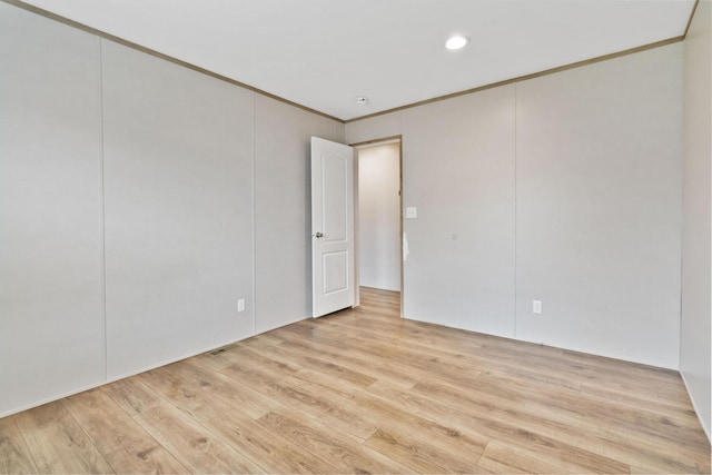 unfurnished room featuring ornamental molding and light hardwood / wood-style flooring