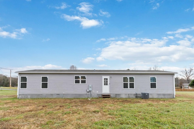 rear view of house featuring central AC unit and a yard