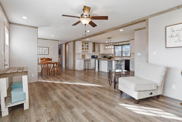 interior space with ornamental molding, light wood-type flooring, and ceiling fan