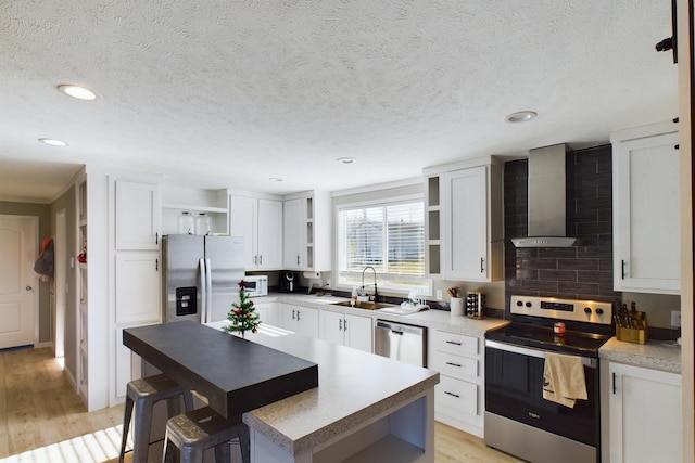 kitchen with light wood-type flooring, a center island, stainless steel appliances, and white cabinetry