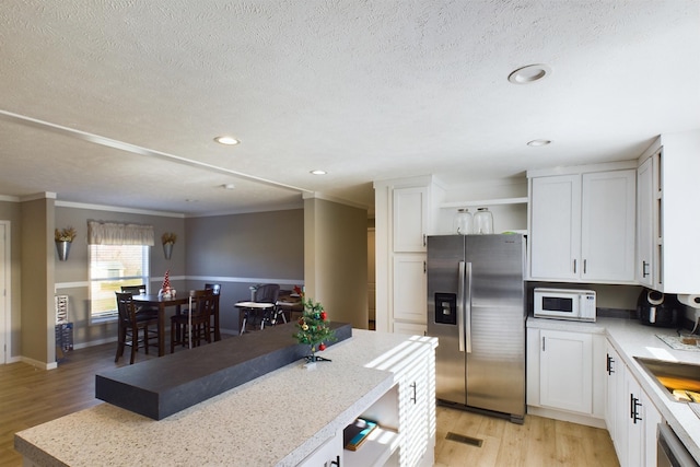 kitchen with white cabinets, stainless steel appliances, light hardwood / wood-style flooring, and ornamental molding