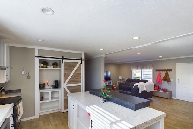 kitchen featuring white cabinets, a barn door, light wood-type flooring, ornamental molding, and black dishwasher