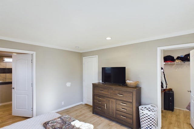 bedroom featuring a walk in closet, a closet, and light hardwood / wood-style flooring