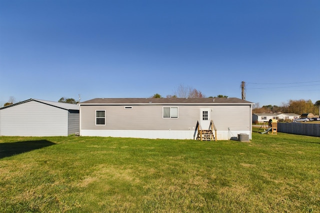 rear view of property featuring central air condition unit and a lawn