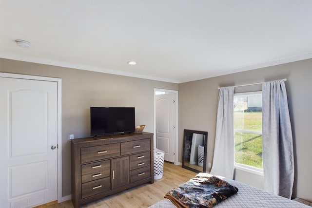 bedroom featuring crown molding and light hardwood / wood-style flooring