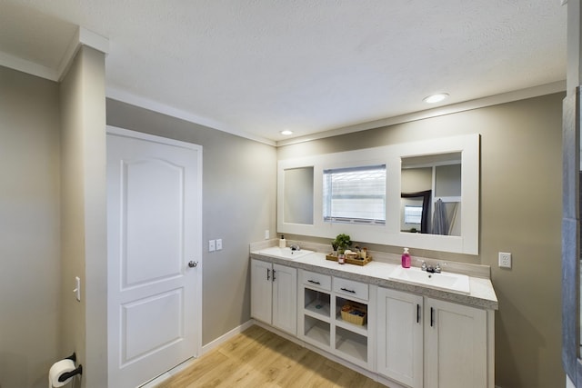 bathroom with a textured ceiling, vanity, hardwood / wood-style flooring, and crown molding