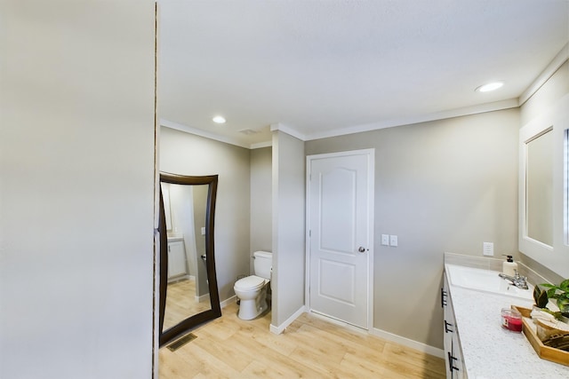 bathroom with crown molding, hardwood / wood-style floors, vanity, and toilet