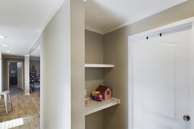 corridor with ornamental molding and light hardwood / wood-style flooring