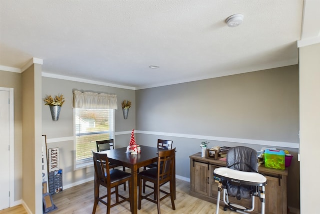 dining area featuring ornamental molding, a textured ceiling, and light wood-type flooring