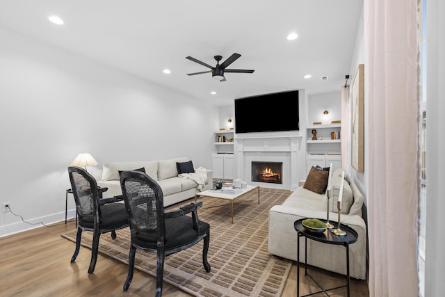 living room featuring ceiling fan, wood-type flooring, and built in features