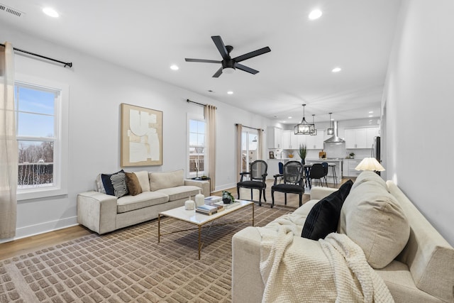 living room with hardwood / wood-style floors and ceiling fan with notable chandelier