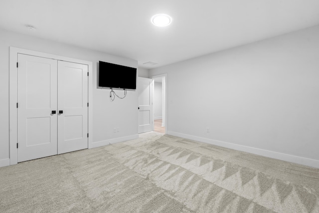 unfurnished bedroom with light colored carpet and a closet